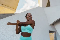 Young African woman in sportswear performing warm up stetches