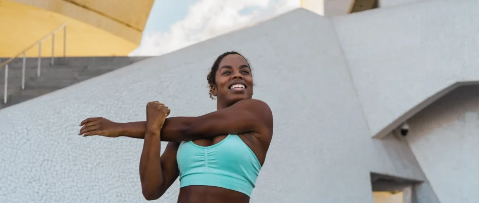 Young African woman in sportswear performing warm up stetches