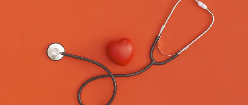 Stethoscope and small red heart against orange backdrop