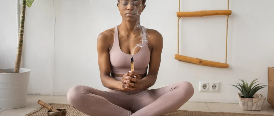 African woman sitting with legs crossed burning sage
