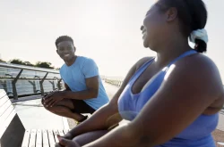 African couple dressed in sports attire stretching before exercising