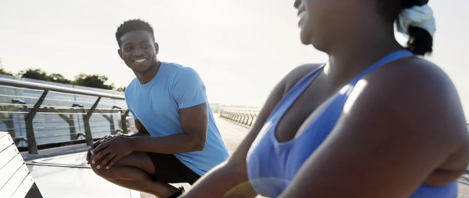 African couple dressed in sports attire stretching before exercising