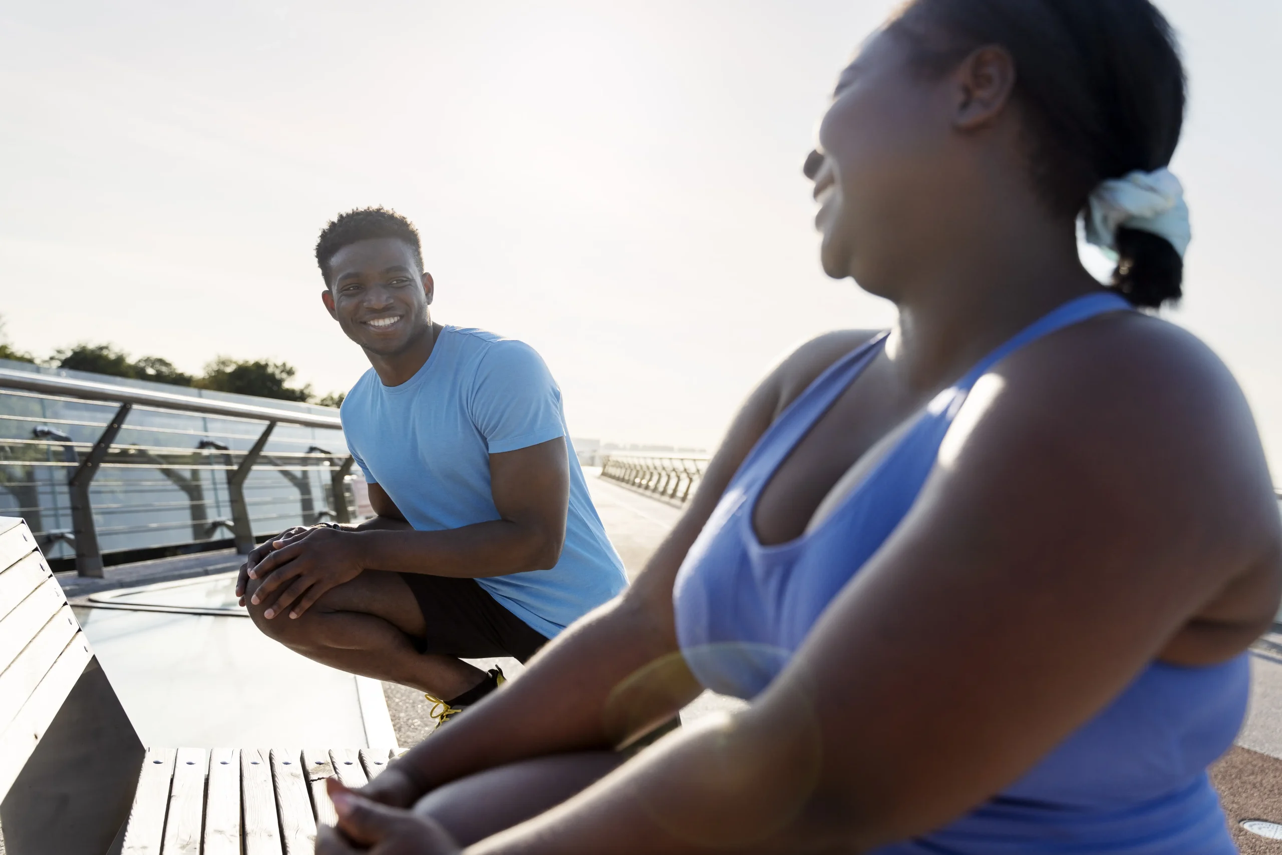 African couple dressed in sports attire stretching before exercising