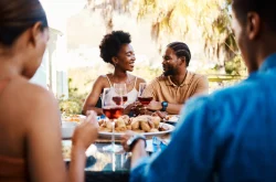 Group of friends sitting around a table dining and drinking wine