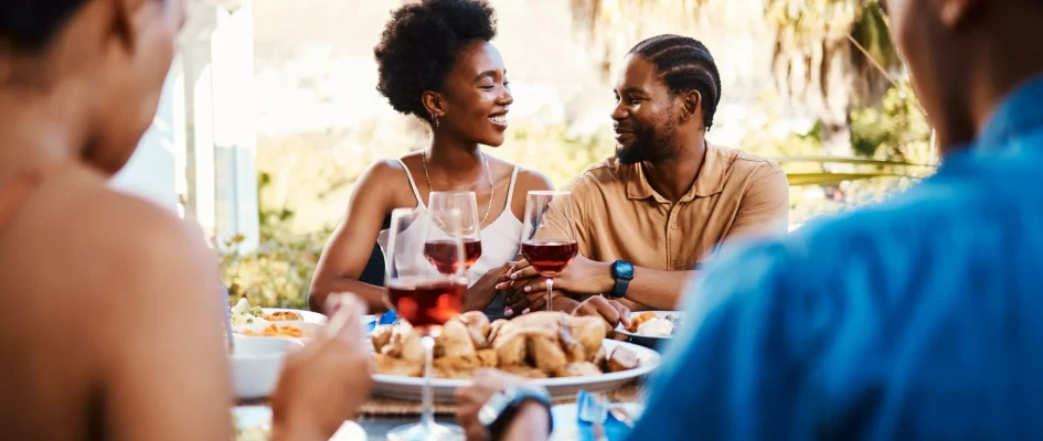 Group of friends sitting around a table dining and drinking wine