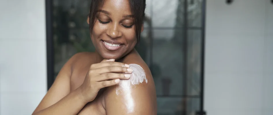 African woman applying sun cream to her shoulder