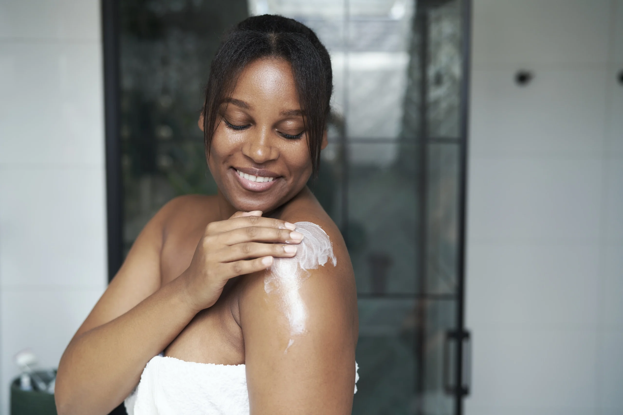 African woman applying sun cream to her shoulder