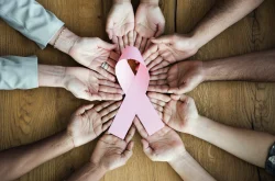 Group of woman holding out hands holding a pink cancer ribbon