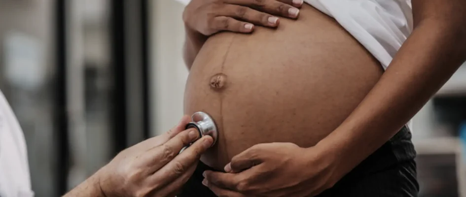 African female with pregnant belly undergoing examination from a male gynaecologist