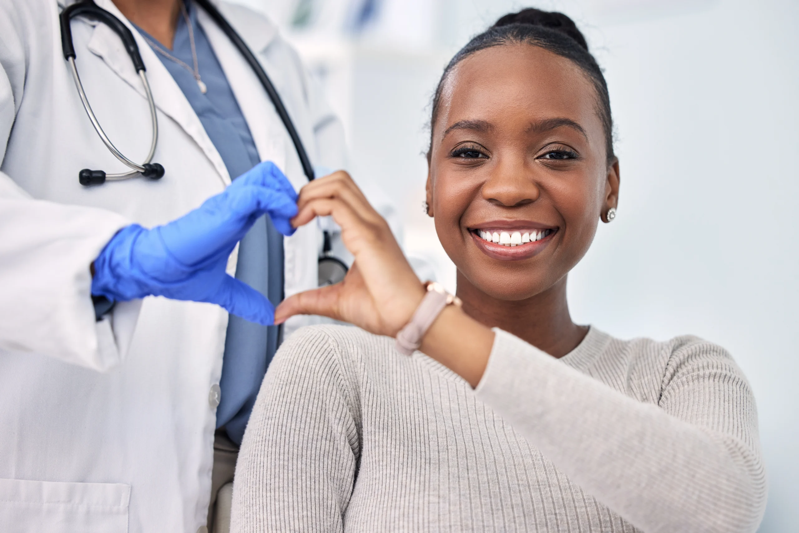 African patient and doctor forming heart shape with their hands