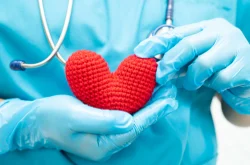 Doctor holding knitted red heart in hands