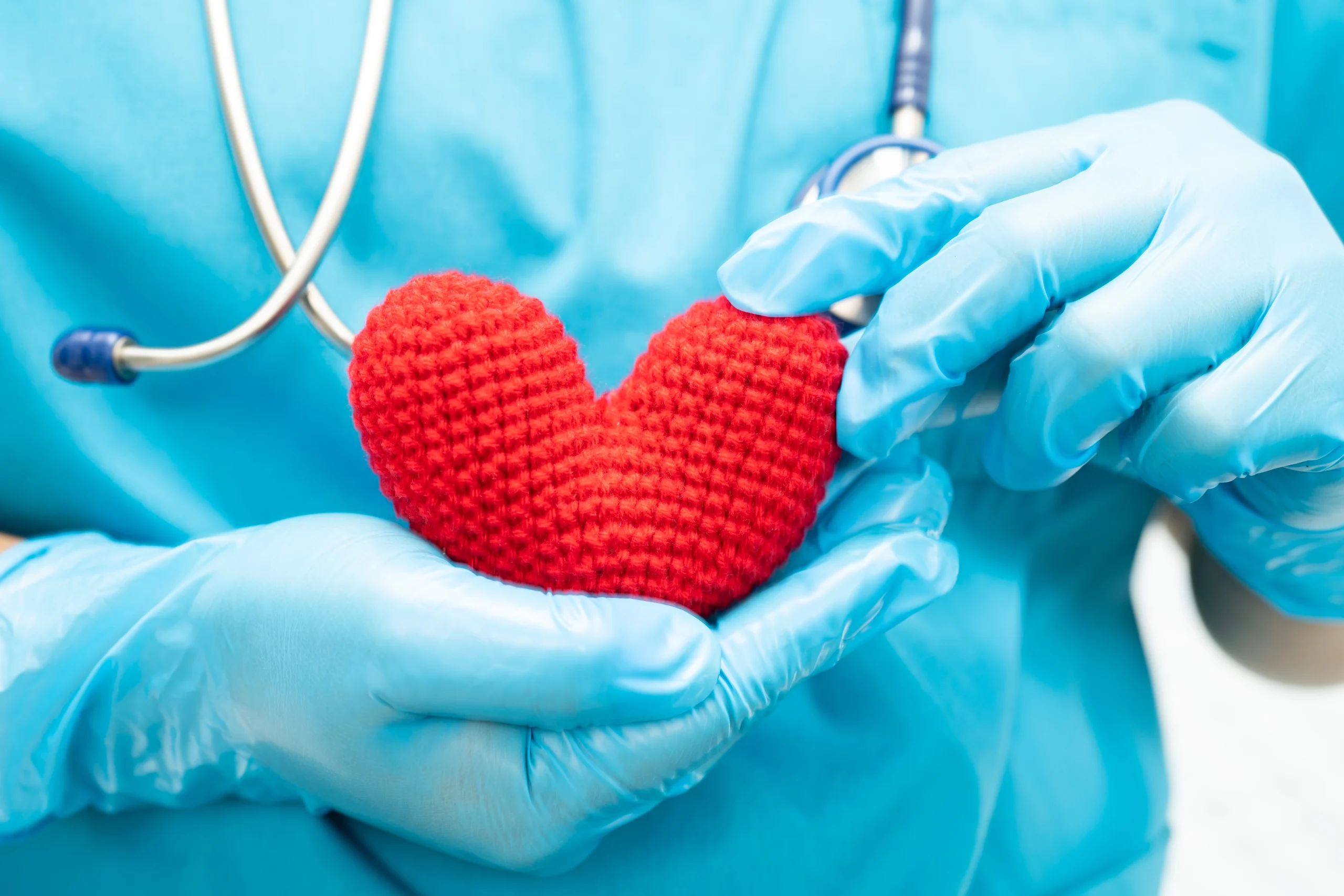 Doctor holding knitted red heart in hands
