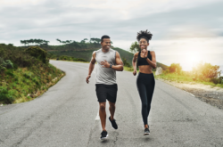 Couple running along road with the sunset in the background