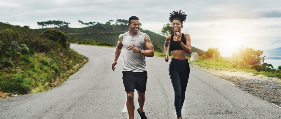 Couple running along road with the sunset in the background
