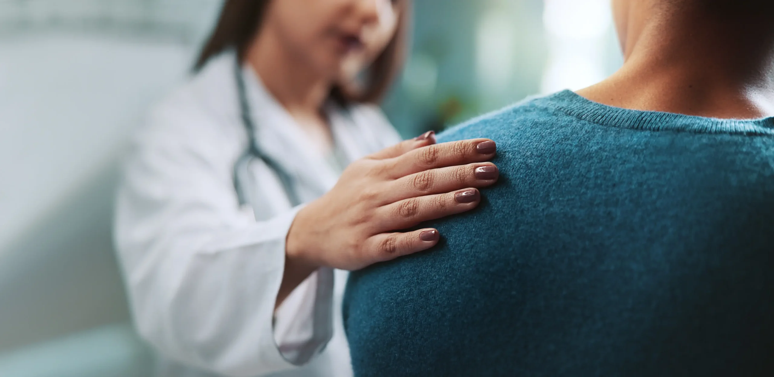 Female doctor consoling patient with her hand on her shoulder