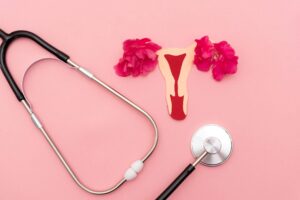 Stethoscope on pink background with uterus cutout alongside
