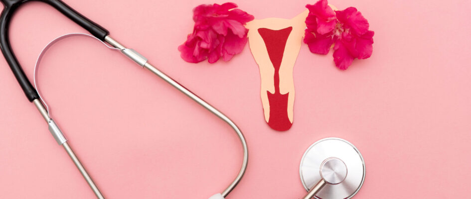 Stethoscope on pink background with uterus cutout alongside