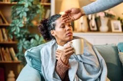home man sick flu health ill virus support care couple together woman partner disease togetherness love boyfriend girlfriend care cure tea cup drink hot Person drinking tea with other person checking forehead temperature with hand
