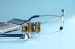 Stethoscope, calculator and coins on light blue background, closeup Stethoscope, calculator and coins on light blue background, closeup