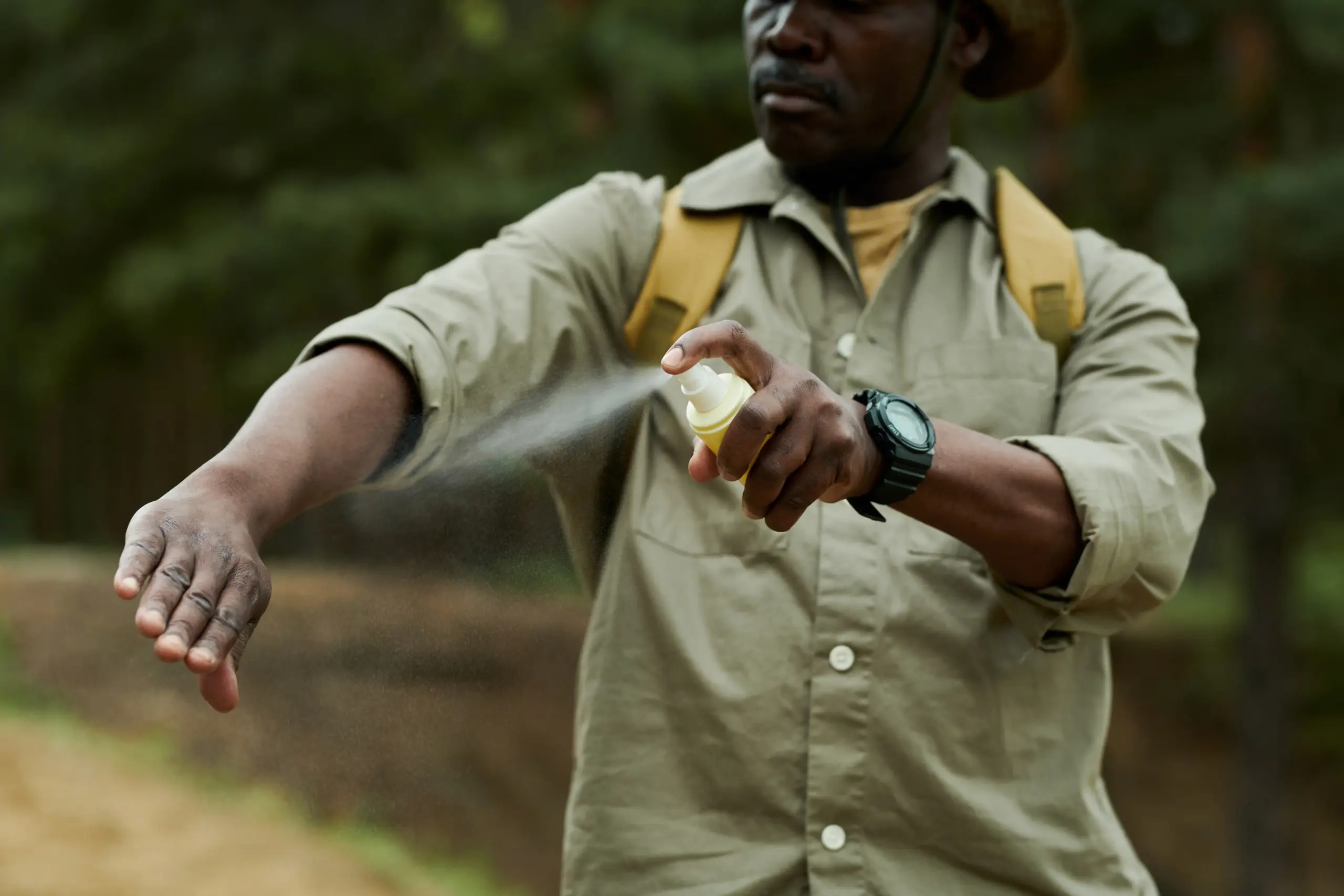 man using mosquito spray outdoors. Malaria