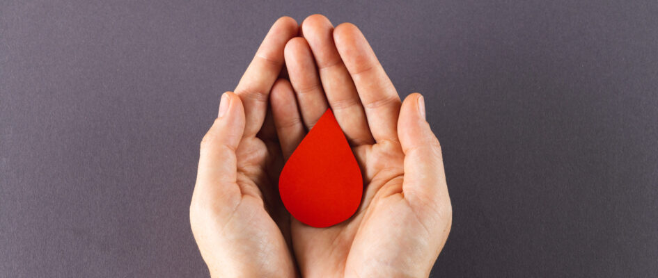 hands holding red blood drop on gray backgrounds