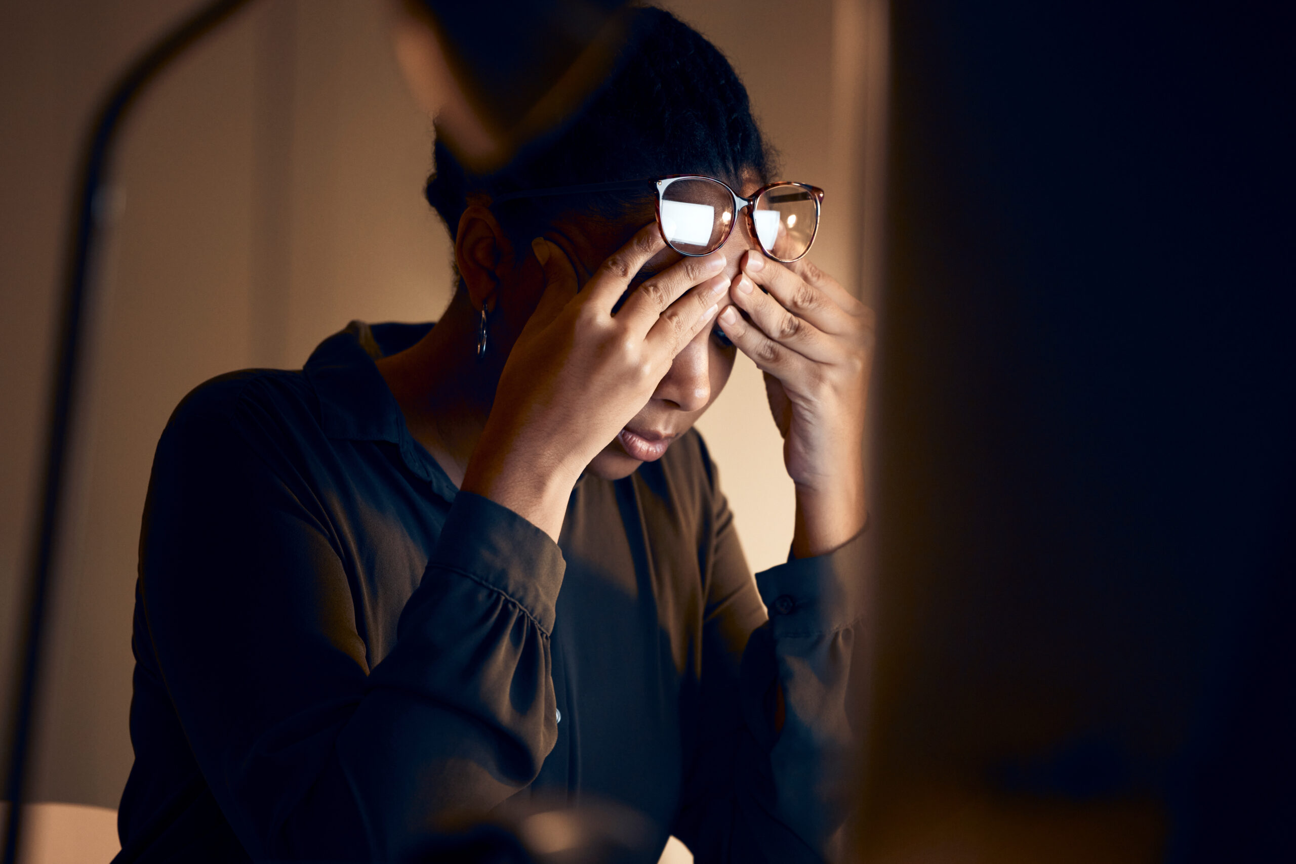 stressed woman with hands on temples at desk