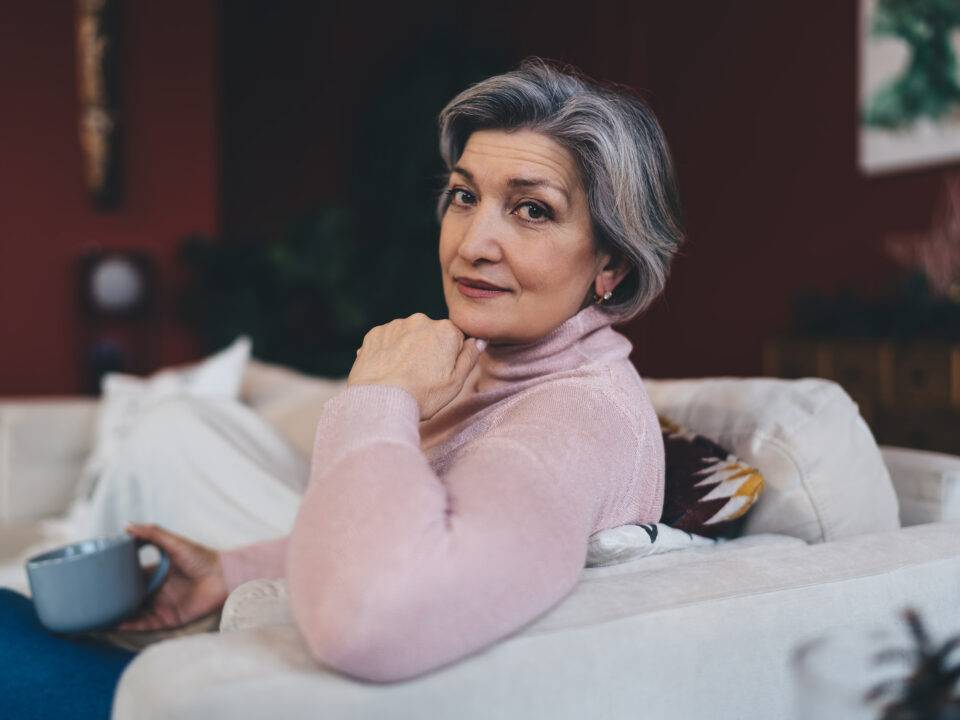thoughtful senior woman relaxing on sofa at home