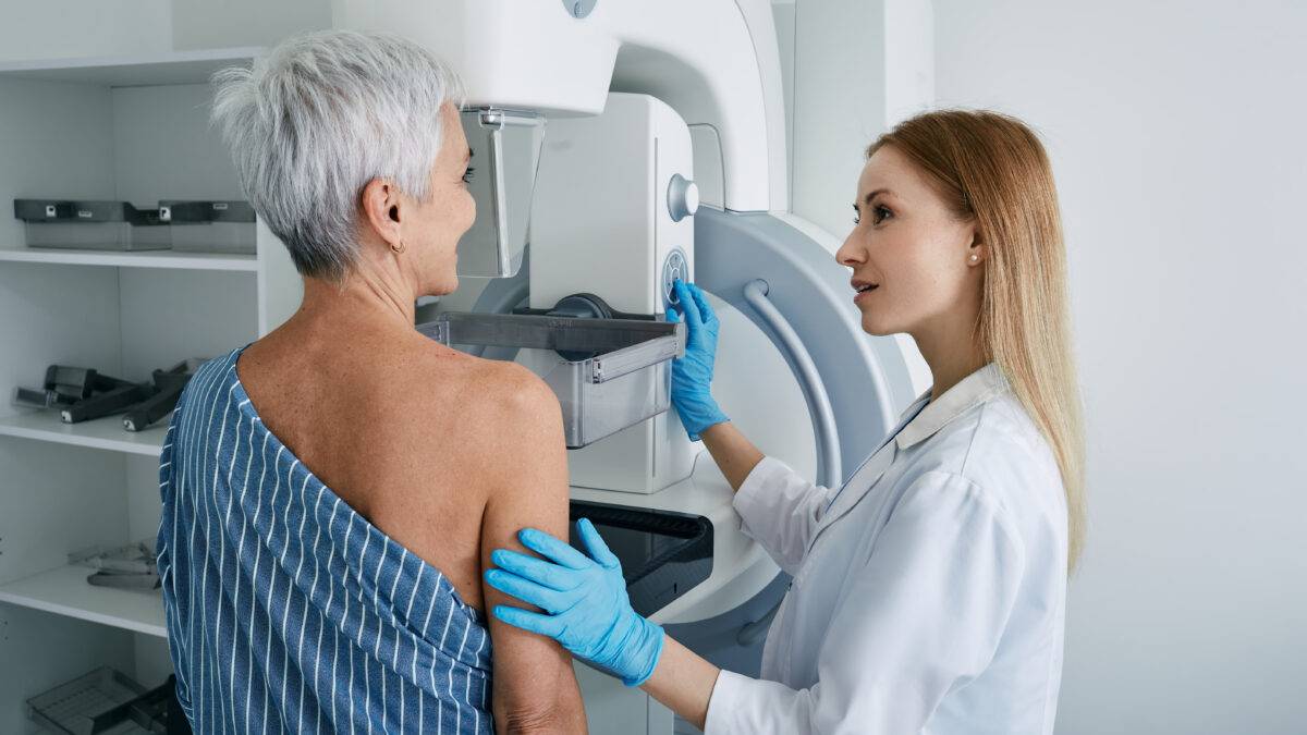 Senior woman having mammography scan at hospital with medical technician. Mammography procedure, breast cancer prevention