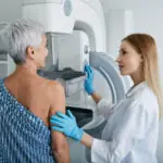 Senior woman having mammography scan at hospital with medical technician. Mammography procedure, breast cancer prevention