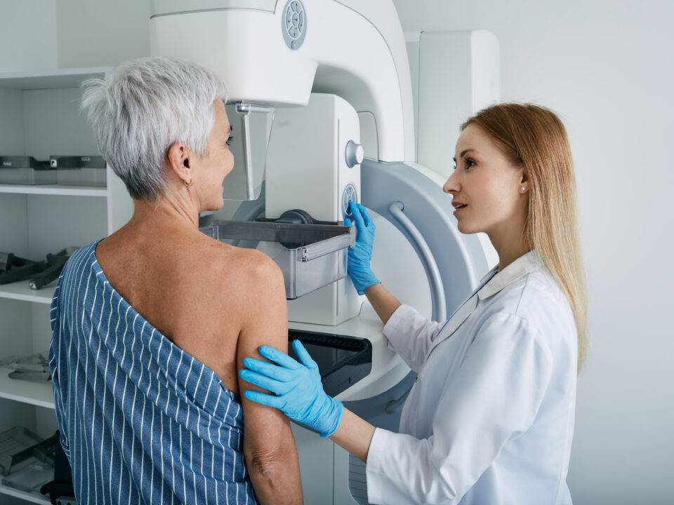 Senior woman having mammography scan at hospital with medical technician. Mammography procedure, breast cancer prevention