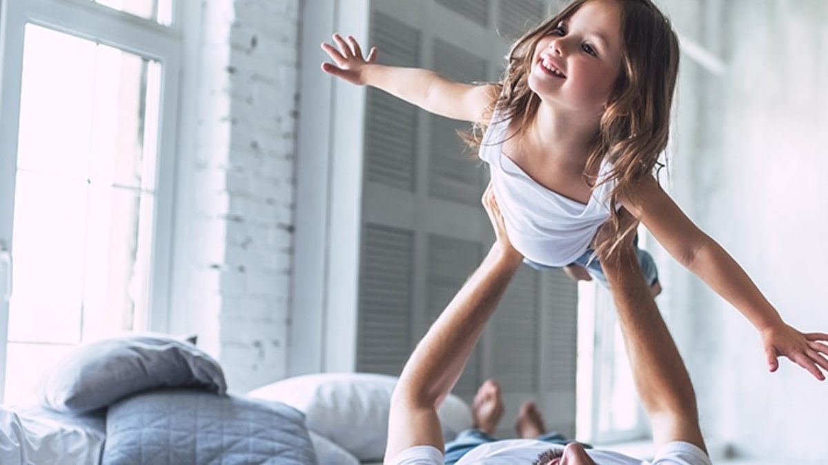 Dad playing with daughter in the bed