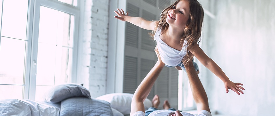 Dad playing with daughter in the bed