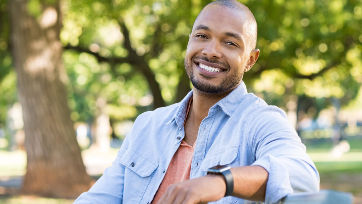 african man smiling while sitting on a bench