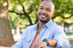 african man smiling while sitting on a bench