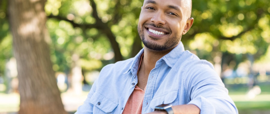 african man smiling while sitting on a bench