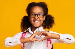 child wearing glasses making a heart shape with hands