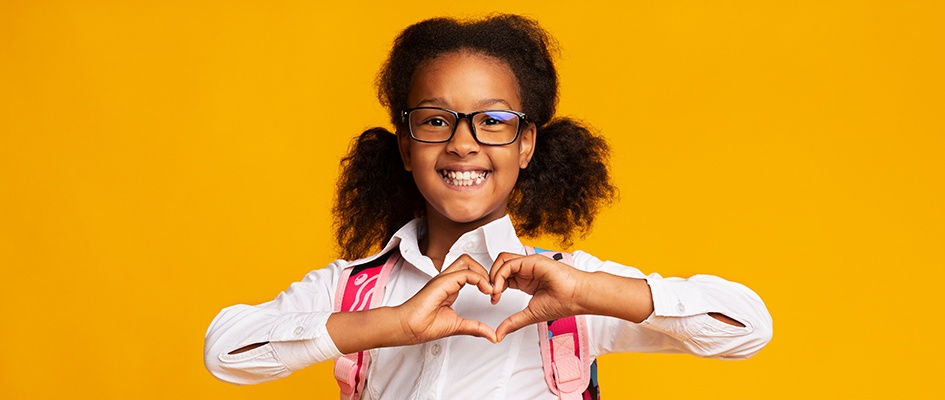 child wearing glasses making a heart shape with hands