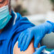 Female doctor vaccinating senior male patient