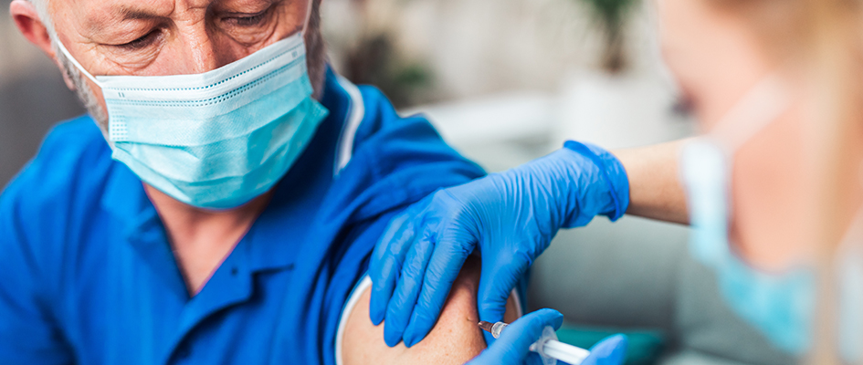 Female doctor vaccinating senior male patient