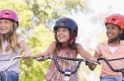 three girls smiling on their bicycles