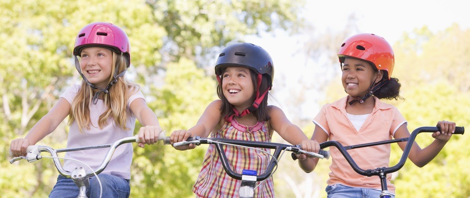 three girls smiling on their bicycles
