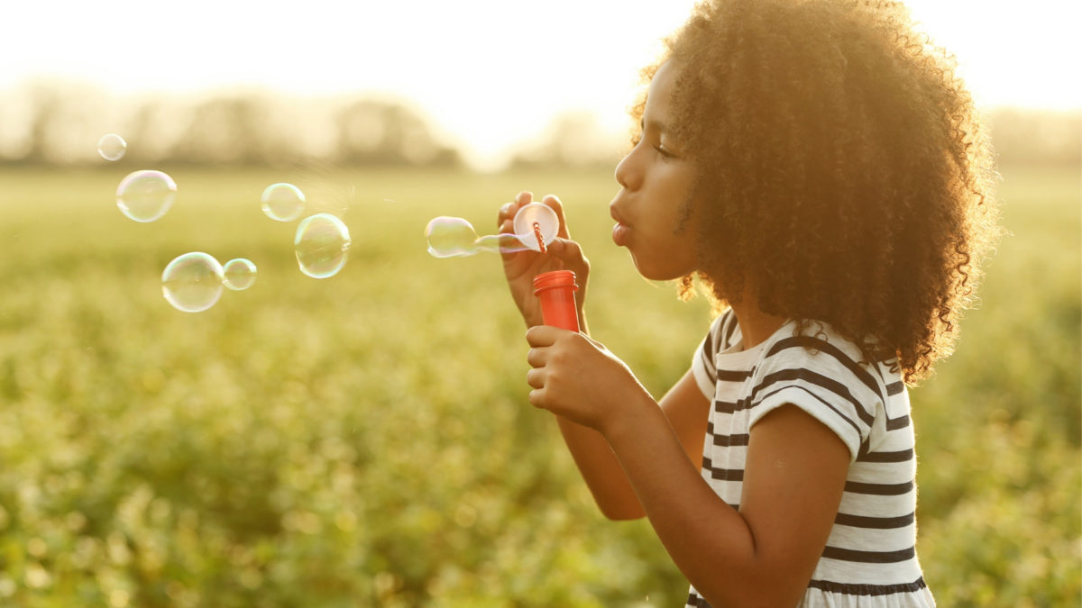 child blowing out bubbles