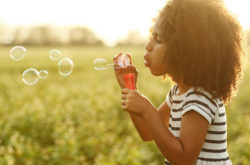 child blowing out bubbles