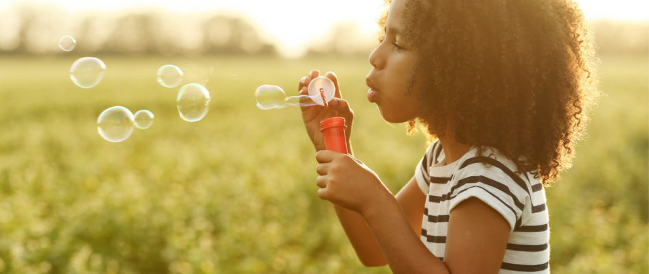 child blowing out bubbles