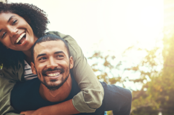 smiling male partner piggybacking smiling female partner