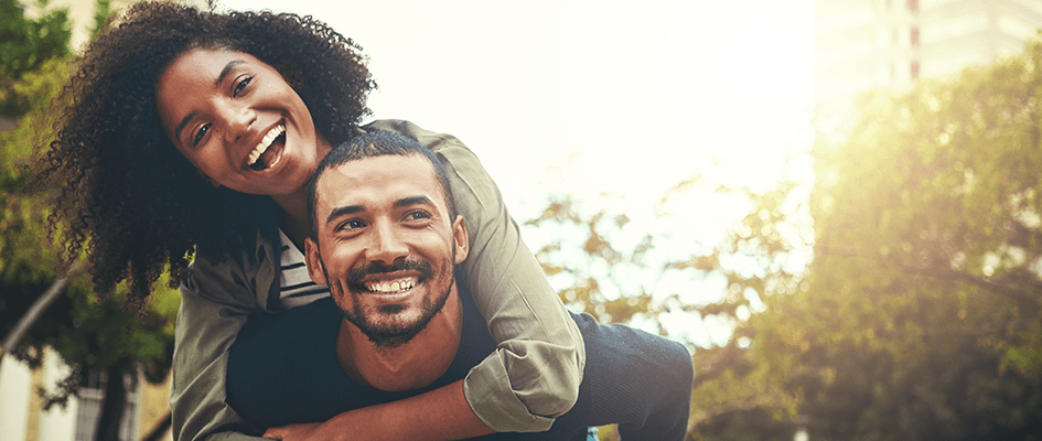 smiling male partner piggybacking smiling female partner