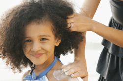 mother applying lotion on daughter's shoulder