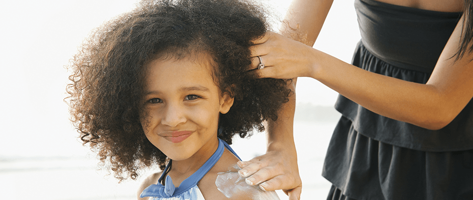 mother applying lotion on daughter's shoulder