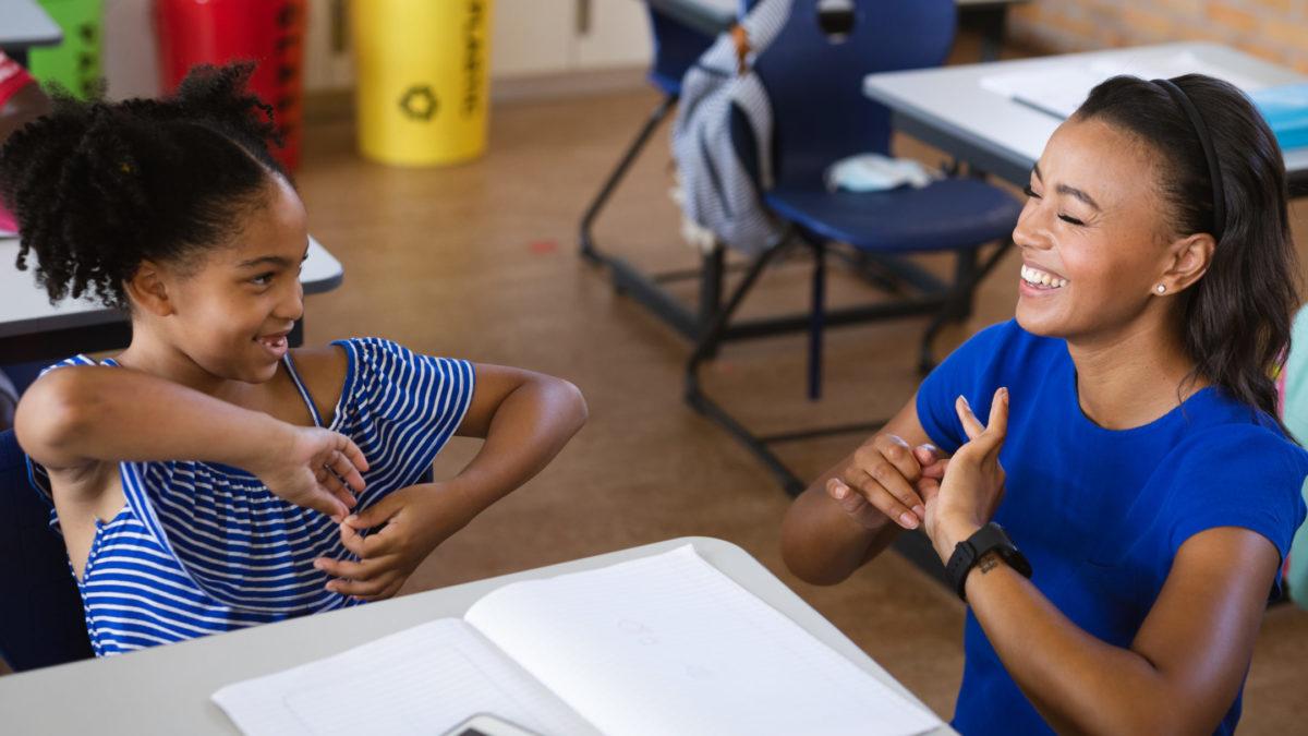 African american female teacher and a girl talking in hand sign language