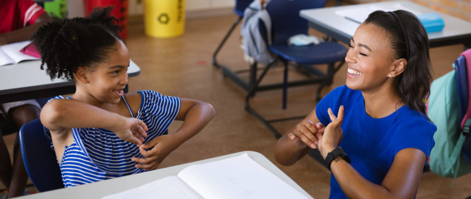 African american female teacher and a girl talking in hand sign language